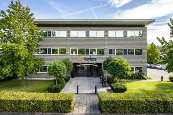 Vooraanzicht van het kantoorgebouw van Keylane aan de Jan Leentvaarlaan, omgeven door groen en parkeerplaatsen.